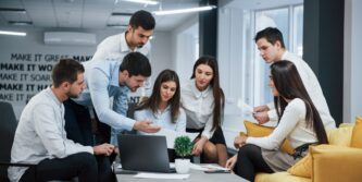 Guy shows document to a girl. Group of young freelancers in the office have conversation and working